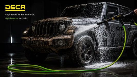 A black Jeep being washed with a thick layer of foam from a high-pressure cannon, featuring the bright green DECA TPU hose lying flexibly on the ground, representing a professional mobile detailing setup.